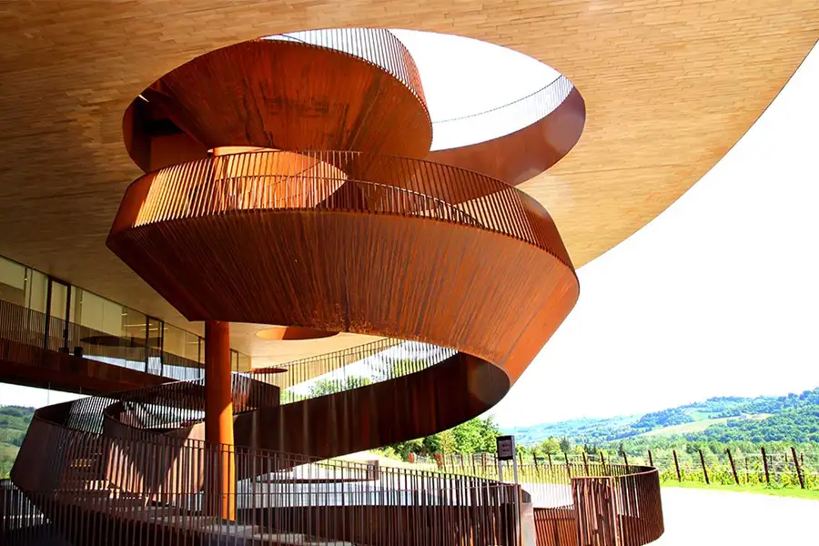 Escadaria em espiral de design moderno na vinícola Antinori nel Chianti Classico, com estrutura de aço corten e vista para os vinhedos da Toscana ao fundo.